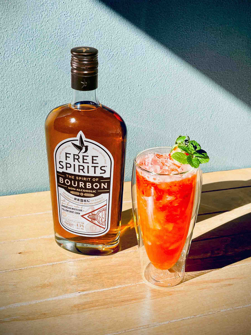 The Spirit of Bourbon with the Kentucky Kiss cocktail on a wood surface with a blue wall
