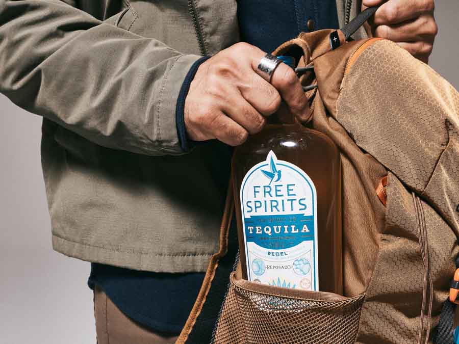 Person opening a bottle of Free Spirits Tequila from a bag.