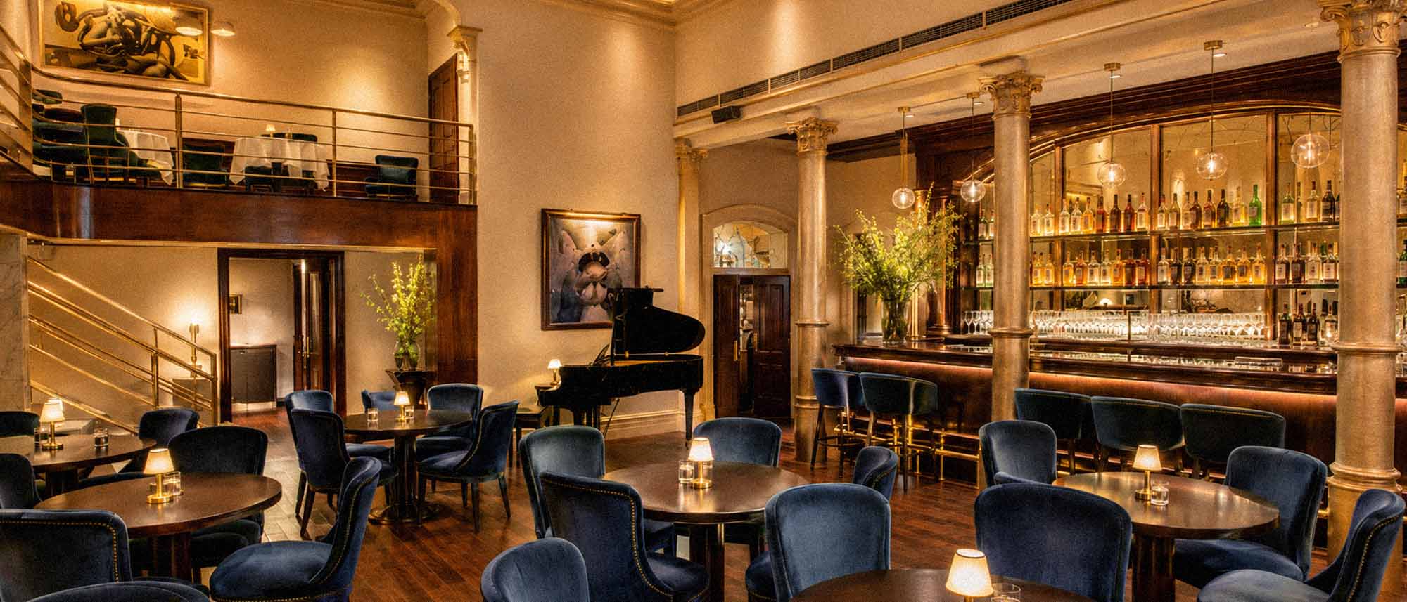 Luxurious interior of a restaurant with elegant decor, including a grand piano and high ceilings.
