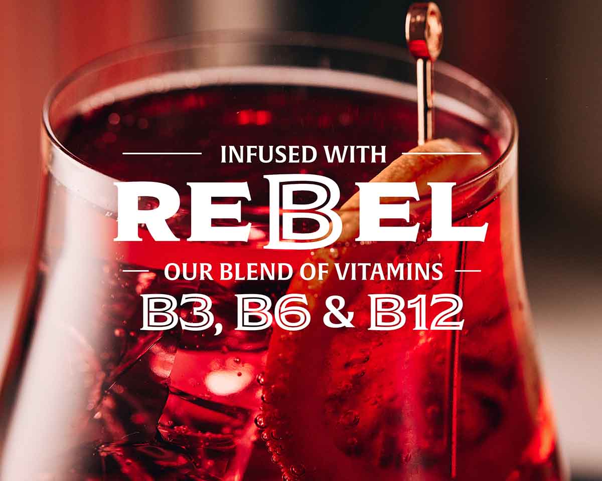 Bitter red aperitivo with lemon slice, infused with Rebel vitamins B3, B6, and B12, on a dark background.