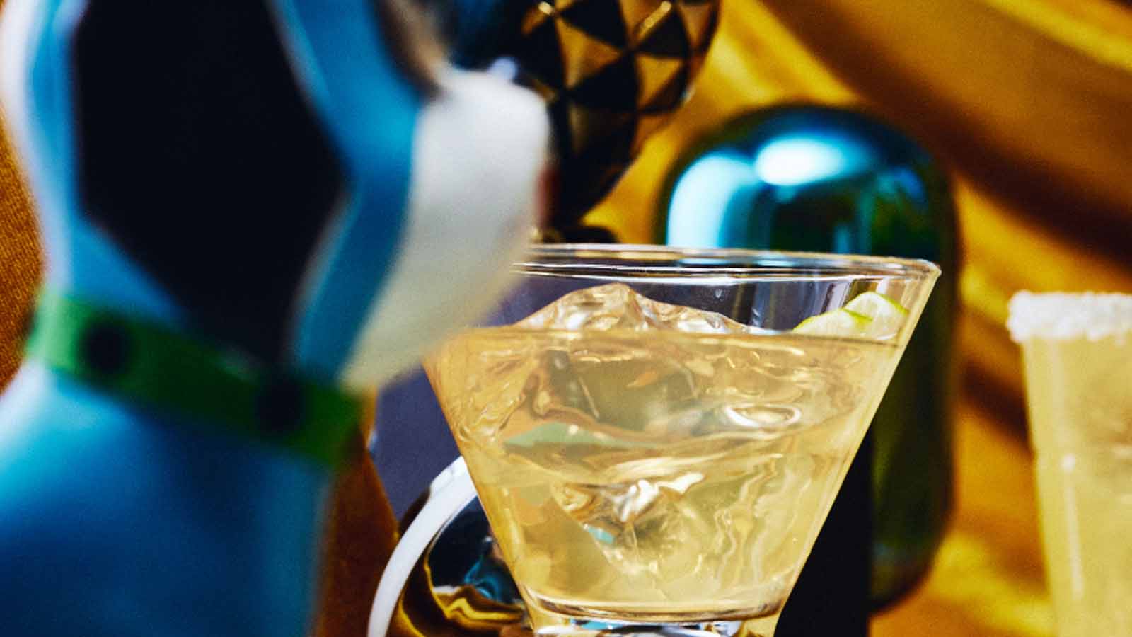 Cocktail in a glass with ice cubes, surrounded by colorful objects.