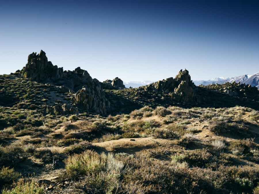 Rugged landscape with rocky outcrops and sparse vegetation under a clear blue sky.