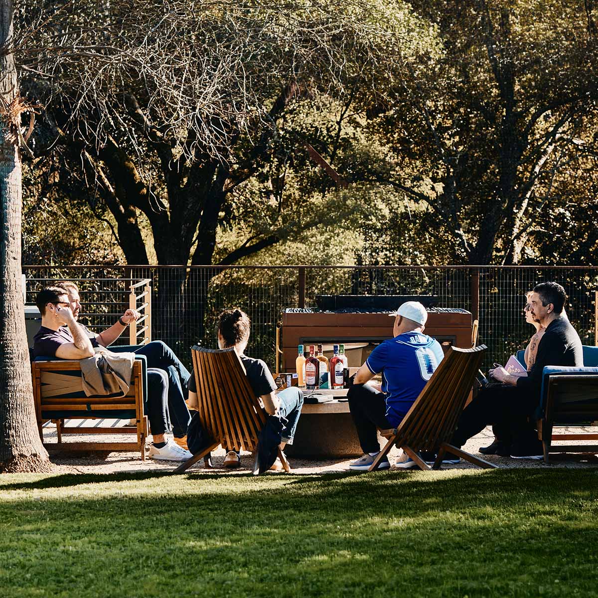 The Free Spirits team sitting outdoors in a park-like setting with trees and having a business meeting
