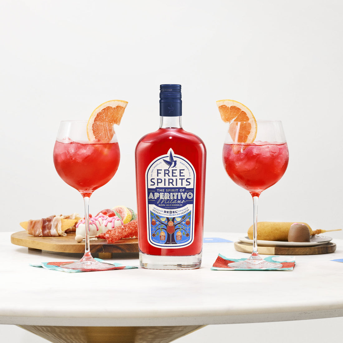 Bottle of Free Spirits aperitivo with two red cocktails on a white surface
