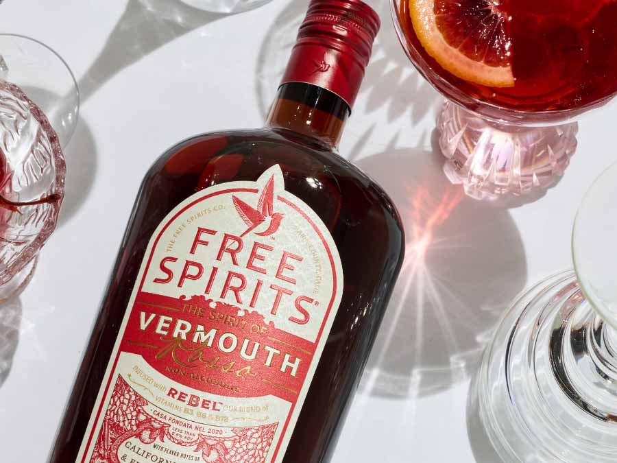 Bottle of Free Spirits Vermouth with glasses on a white surface